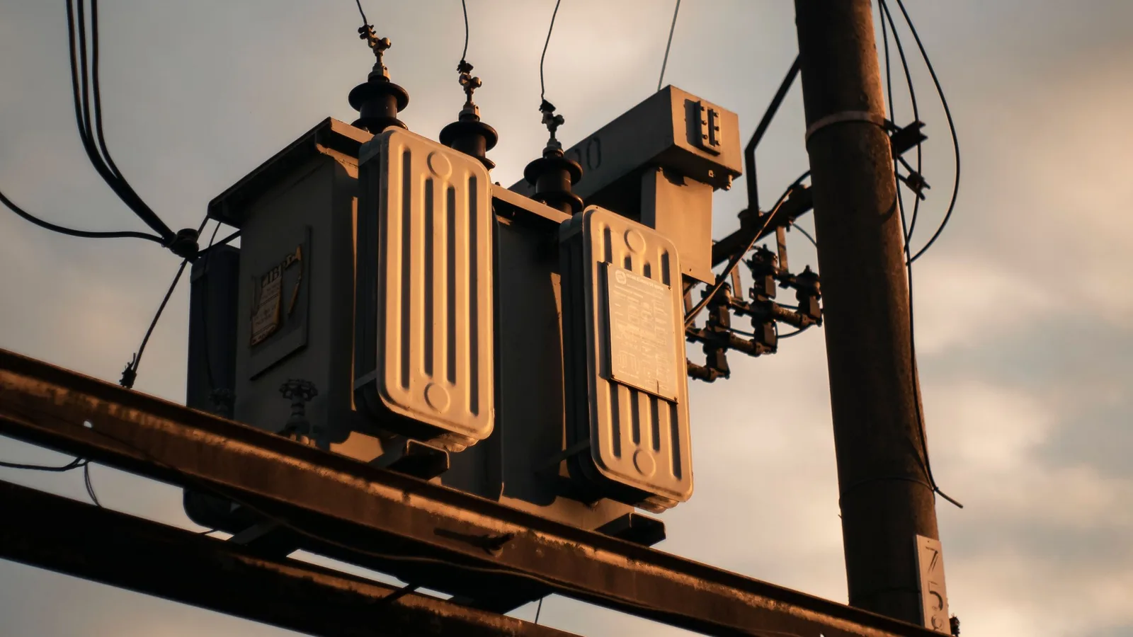 Gün batımında elektrik direği üzerindeki radyatörlü yağlı tip dağıtım trafosu