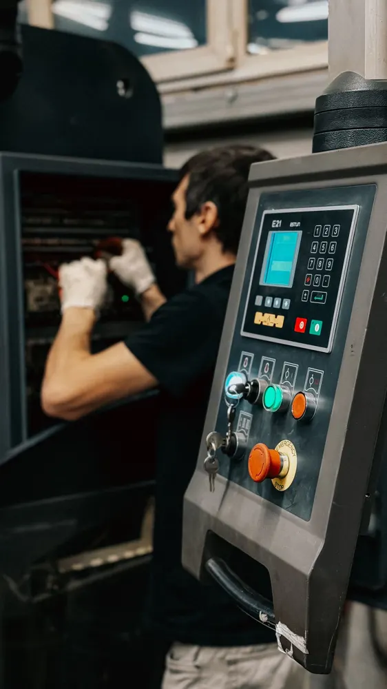 Technician operating an industrial machine control panel